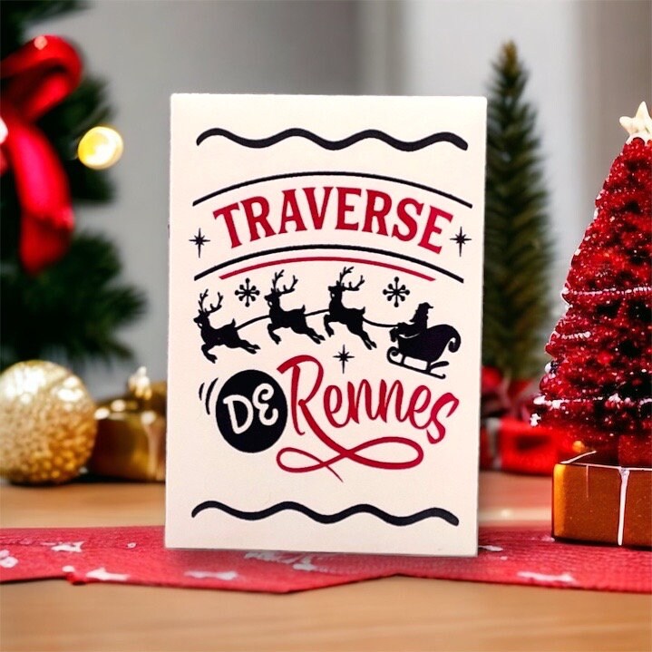 French Christmas seed packet reading 'Traverse de Rennes' with a silhouette of Santa's sleigh pulled by three reindeer, beside a small red Christmas tree decoration