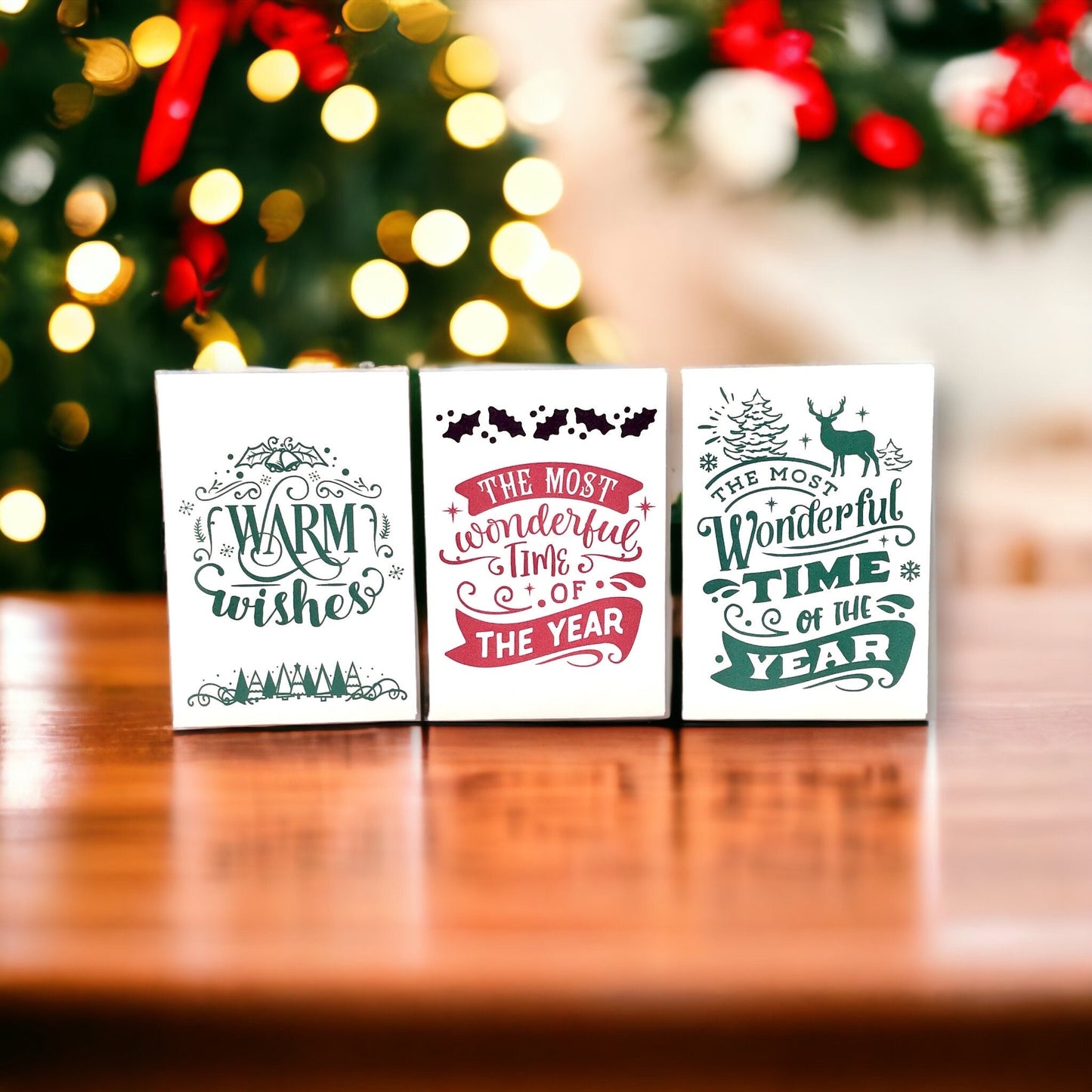 Three vintage-style Christmas seed packets on a wooden table, reading 'Warm wishes' and two versions of 'The most wonderful time of the year' in red and green