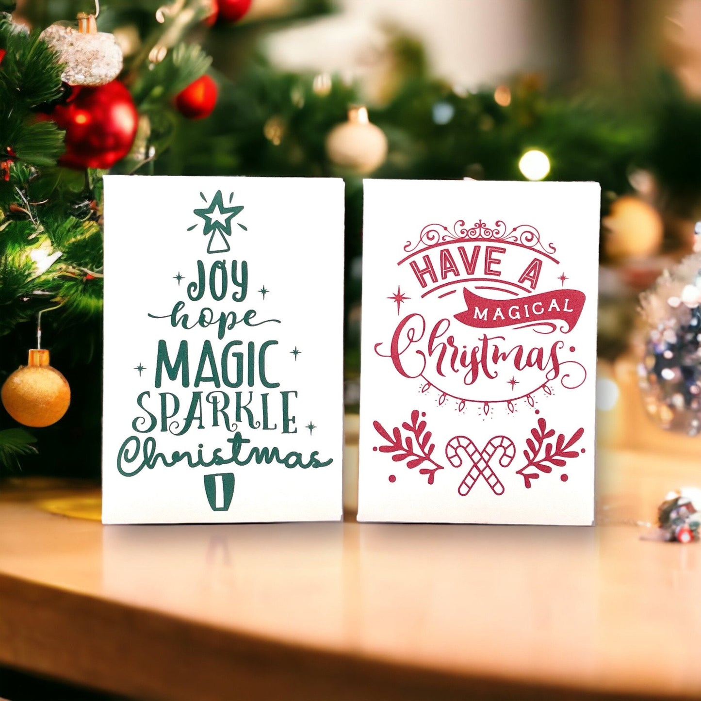 Two vintage-style Christmas seed packets beside a decorated Christmas tree, one with the words 'Joy hope magic sparkle Christmas' arranged in the shape of a tree and one reading 'Have a magical Christmas' with crossed candy canes