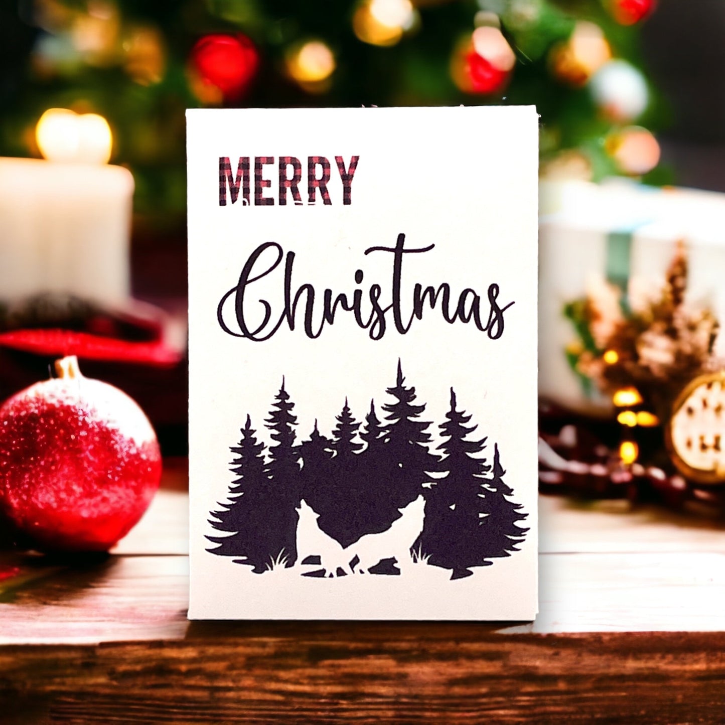 Woodland Christmas seed packet reading 'MERRY Christmas' above a silhouette of two howling wolves in a pine forest, beside a candle and a red bauble